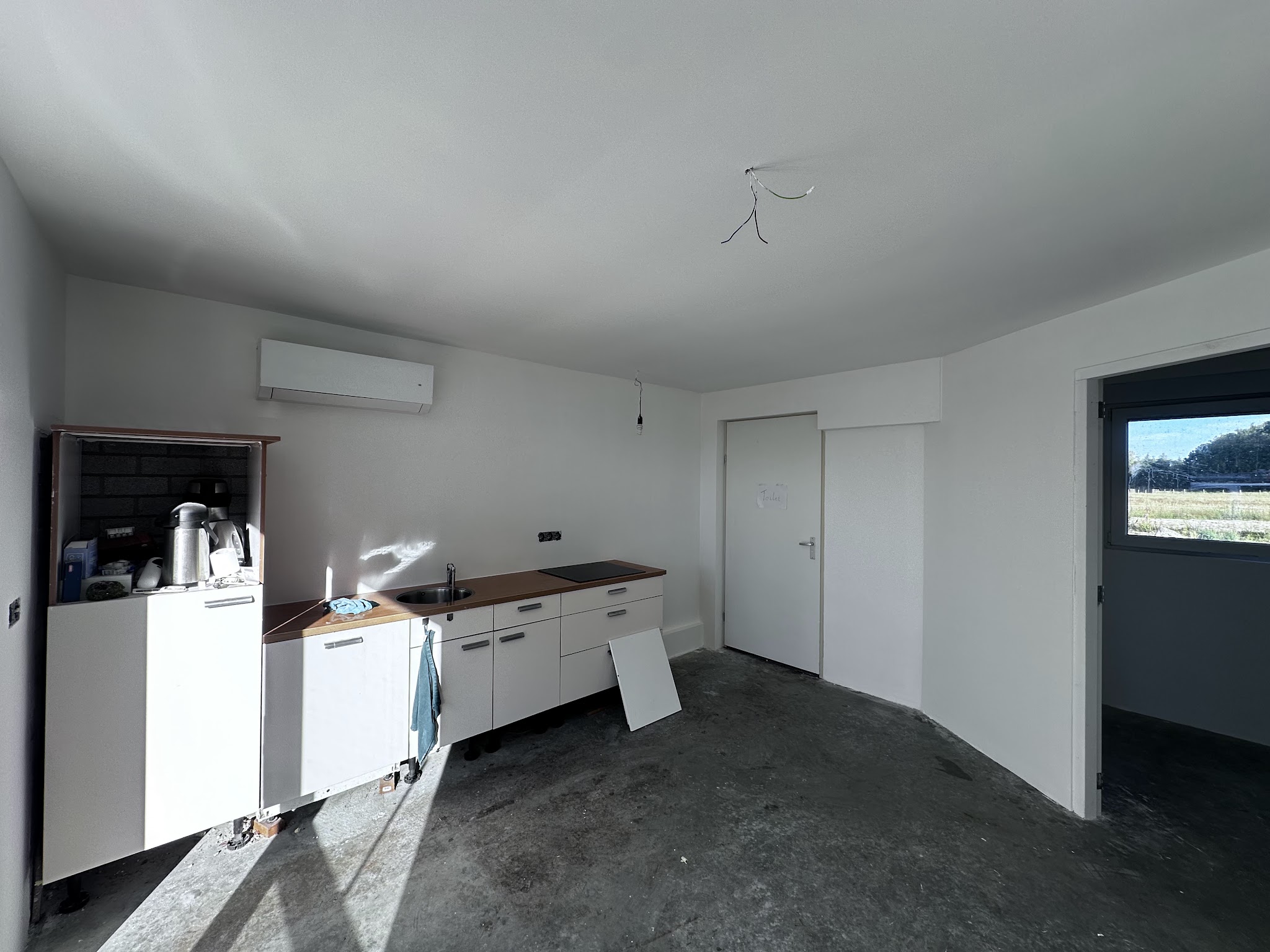 Een pas gestucte kamer, wanden en plafond vlak en wit, de vloer ligt er nog niet in