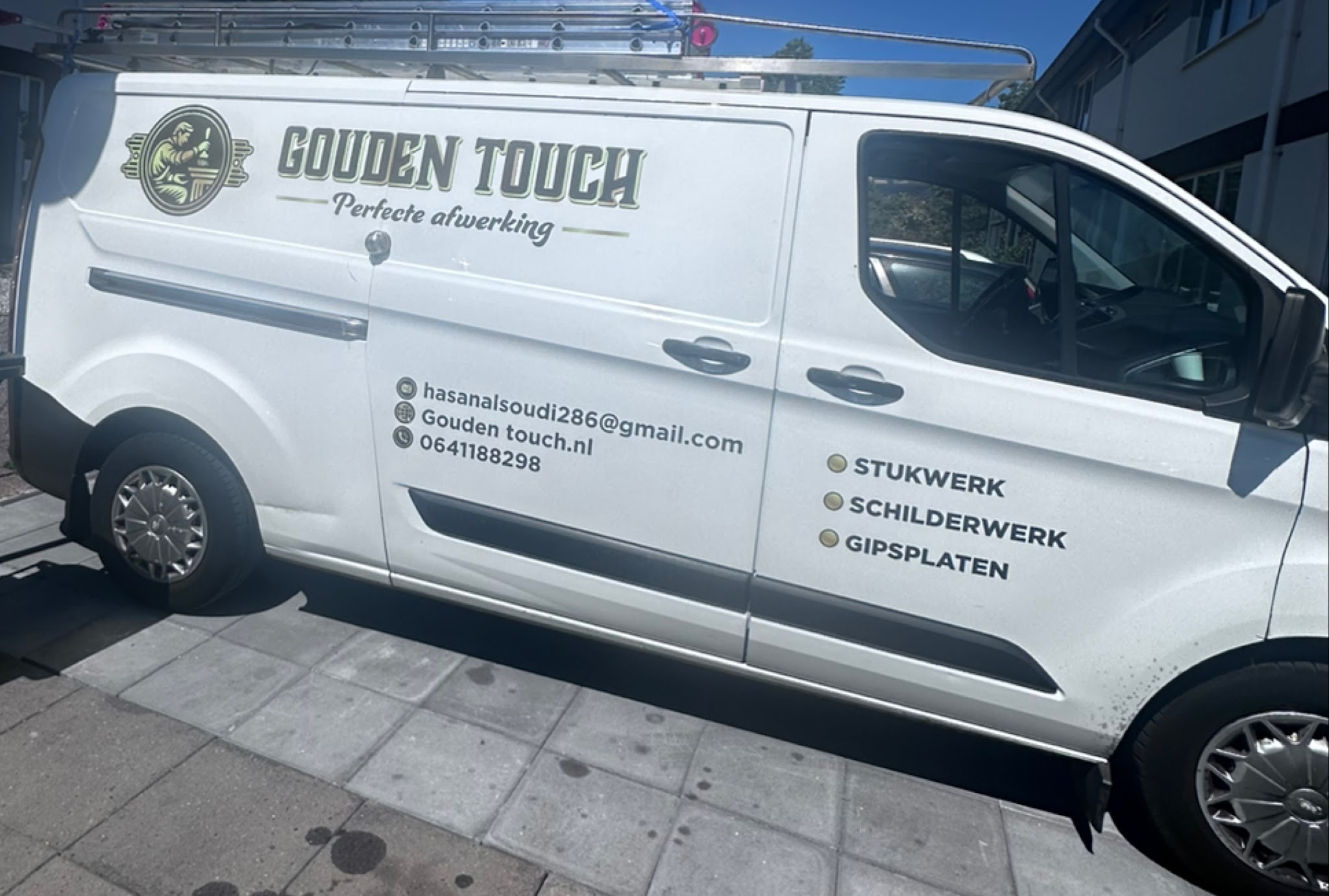 De bus van Gouden Touch met het logo, de leus Perfecte afwerking en de diensten stukwerk, schilderwerk en gipsplaten